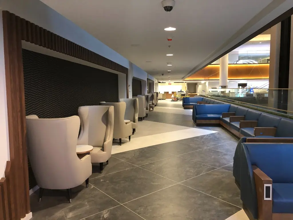 Hospitality Lounge Millwork | Warm Home Inc Hospitality lounge corridor with wood-framed seating, wingback chairs, and custom wall millwork by Warm Home Inc