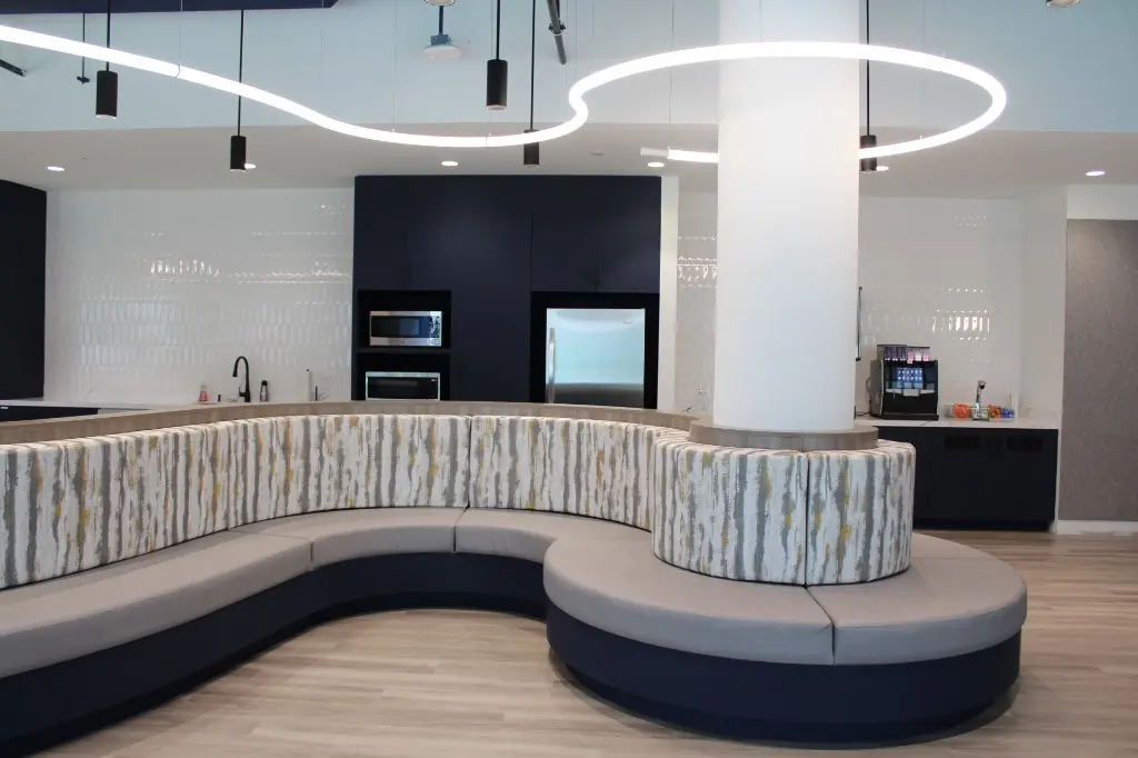Lounge Kitchenette Millwork | Warm Home Inc Commercial lounge with curved banquette seating and navy kitchenette cabinetry by Warm Home Inc