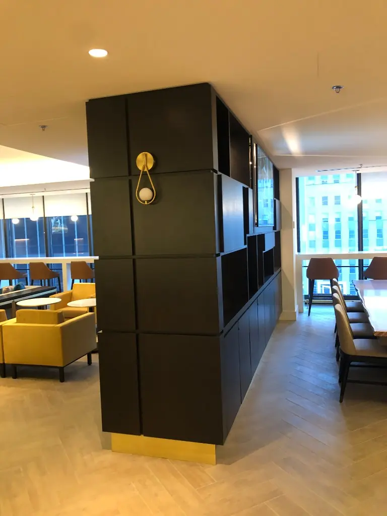 Modular Lounge Cabinetry | Warm Home Inc Floor-to-ceiling charcoal modular cabinetry with gold accents dividing a commercial lounge by Warm Home Inc