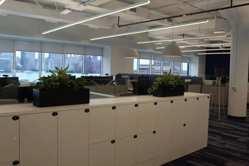 Office Locker and Storage Millwork | Warm Home Inc Modern open office with numbered white locker millwork, planter tops, and wood workstation panels by Warm Home Inc
