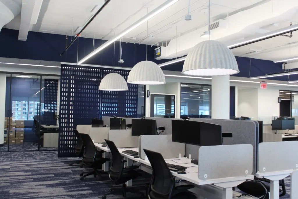 Open Office Desk Millwork | Warm Home Inc Open-plan office with white desk millwork, felt privacy screens, navy perforated divider, and dome pendants by Warm Home Inc