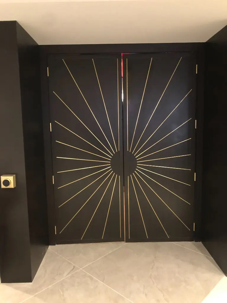 Architectural Feature Doors | Warm Home Inc Matte black double doors with a gold sunburst inlay, custom architectural millwork by Warm Home Inc