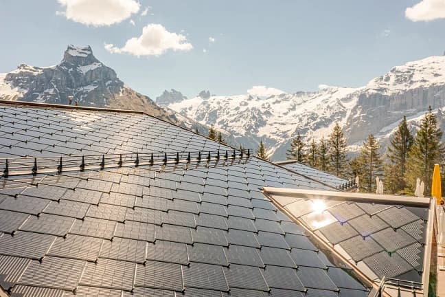 CertainTeed SunStyle Solar Roof Tiles | Warm Home Inc CertainTeed SunStyle solar roof tiles covering a mountain home under clear sky — building-integrated photovoltaic (BIPV) solar roofing by Warm Home Inc