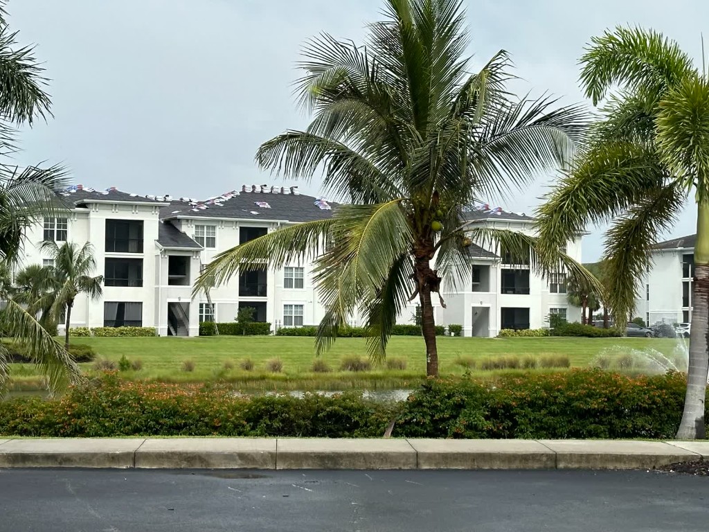 fl-fort-myers-condo-bundles-1.jpg Fort Myers multifamily building with a dark shingle roof and packaged roofing bundles on the ridge