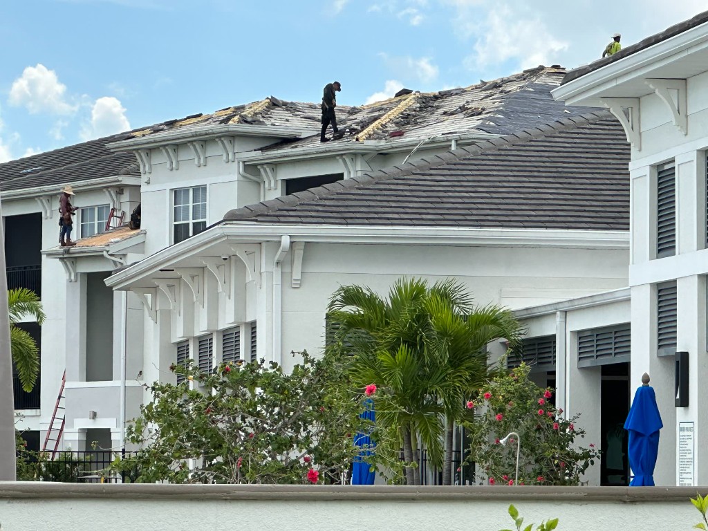 fl-fort-myers-condo-tearoff-1.jpg Fort Myers multifamily roof during tear-off, with decking exposed and crew on the roof