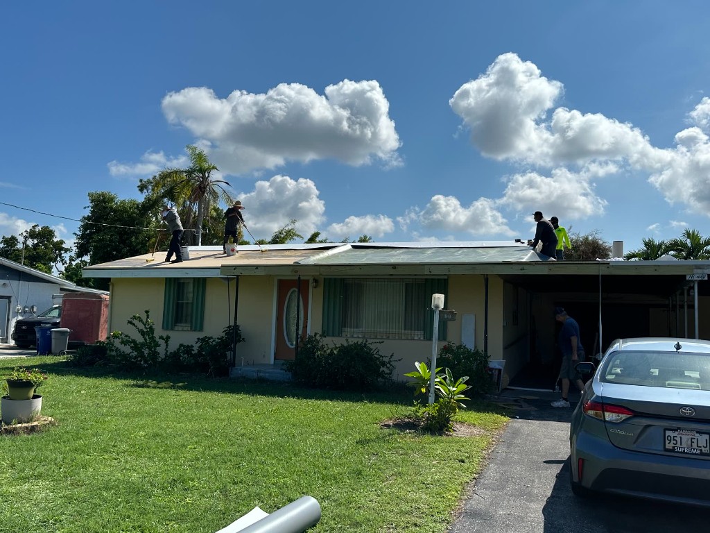 fl-fort-myers-ranch-membrane-1.jpg Fort Myers ranch house with crew working a white membrane on a low-slope roof